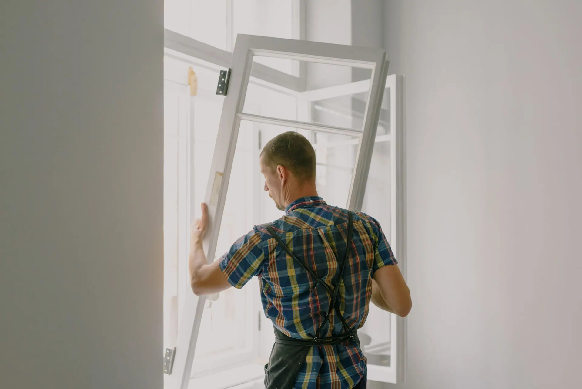 Vakman zet een nieuw wit kozijn in een raamopening