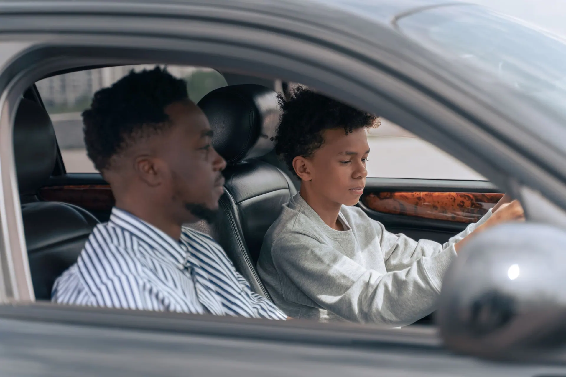 Ruben legt op de bijrijdersstoel uit hoe een leerling het stuur vasthoudt