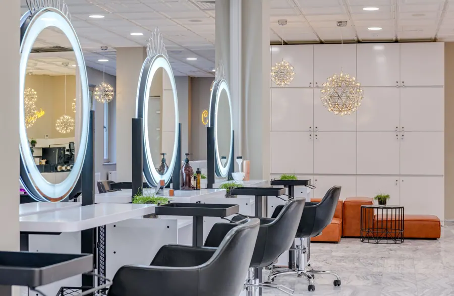 De lichte salon met ronde spiegels en zwarte stoelen