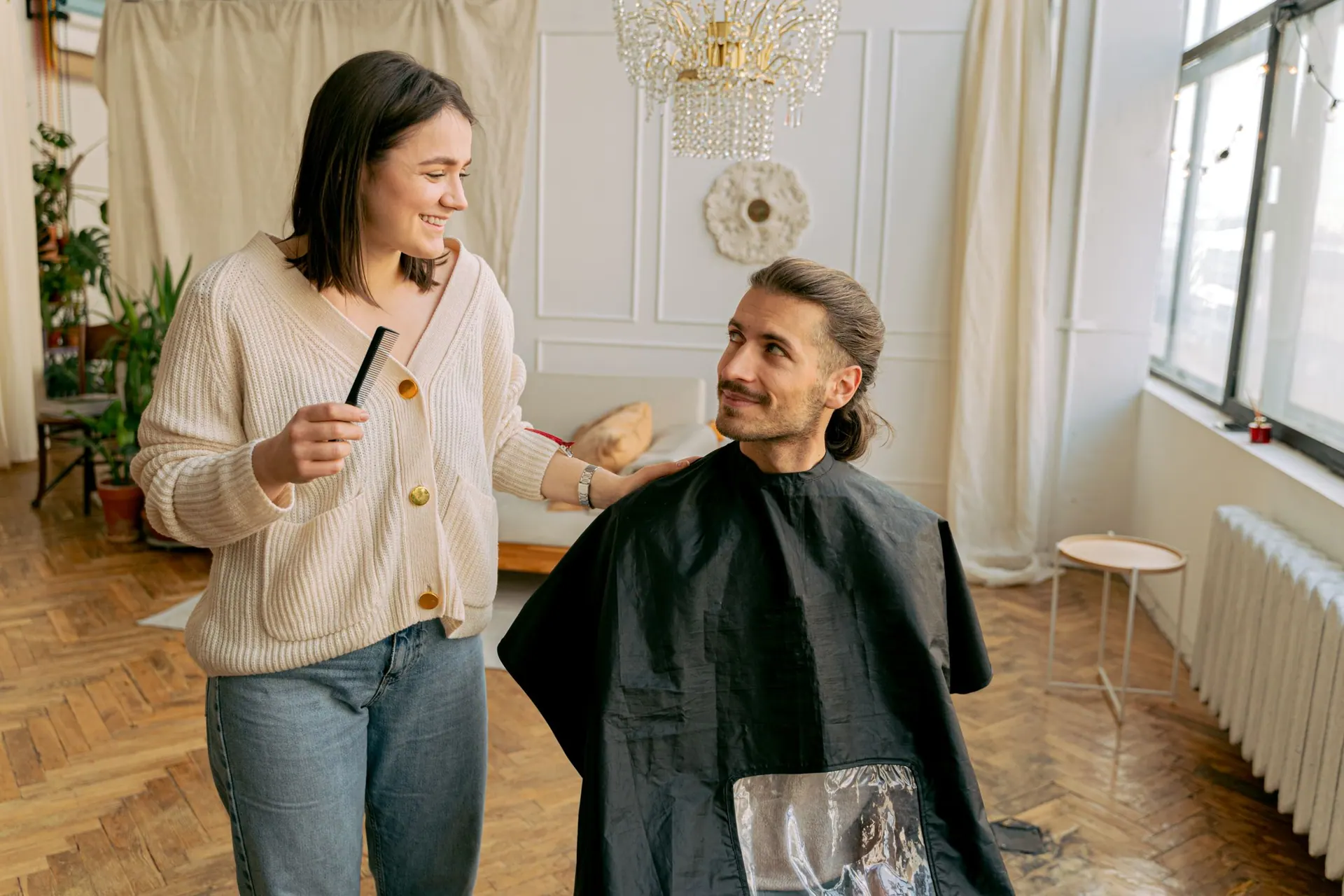 Een kapster stylet het haar van een man met een kam