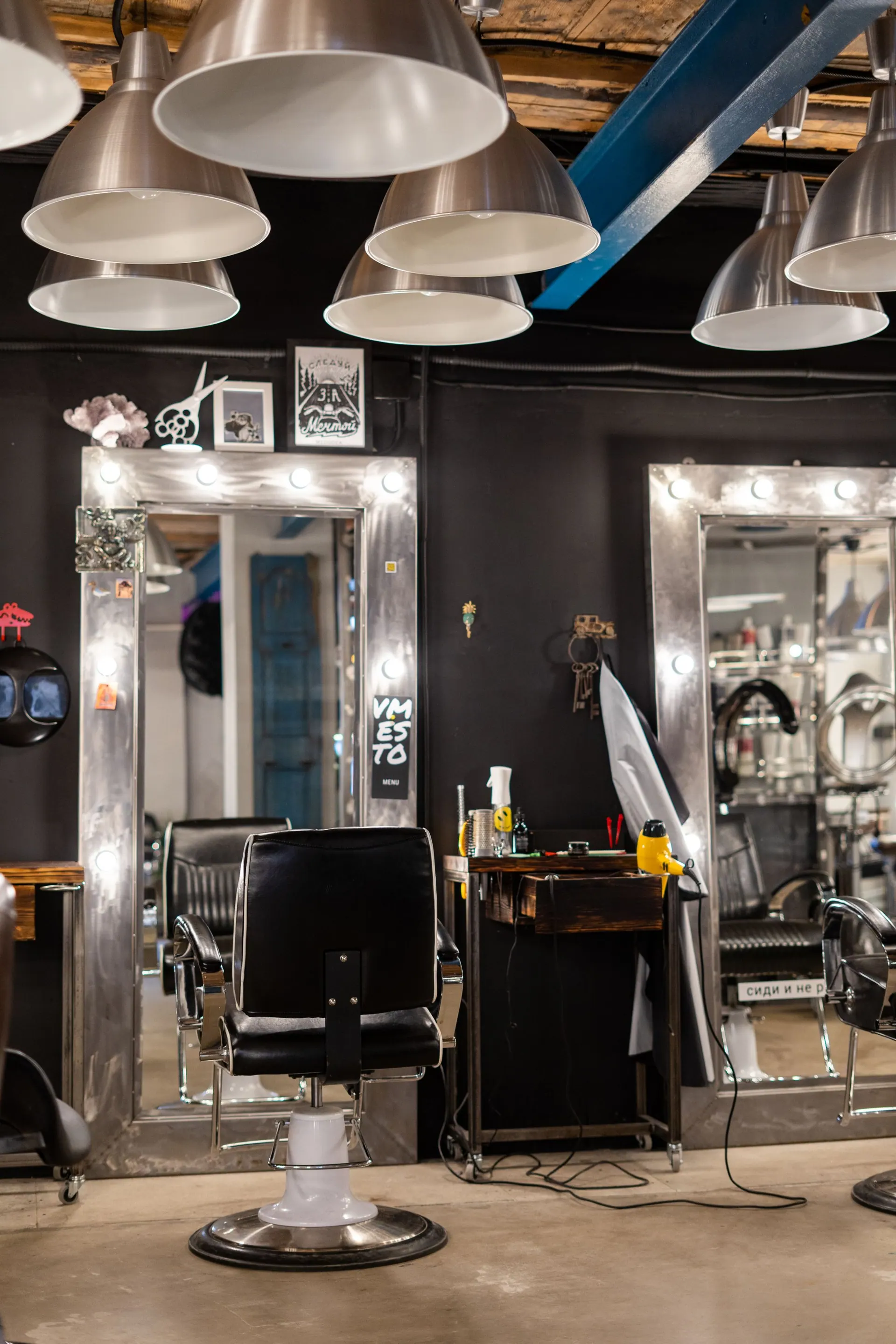 De salon met zwarte stoelen, spiegels met lampjes en hanglampen