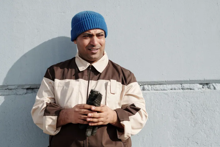 Ravi Mahabier met blauwe muts tegen een lichte muur