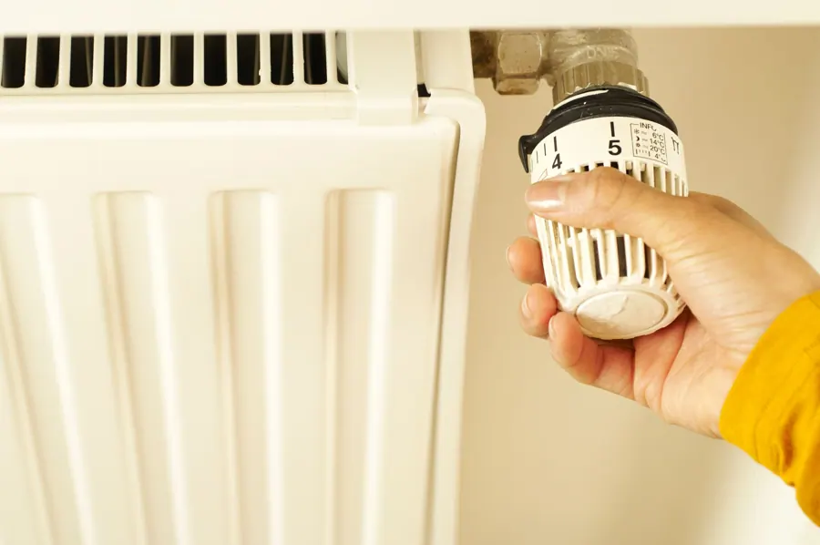 Hand draait aan een thermostaatknop