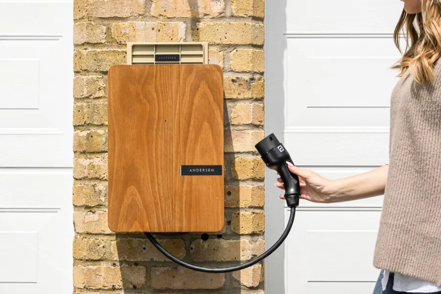 Houten laadpaal aan een bakstenen gevel met een laadkabel